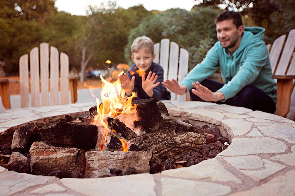 Father and son warming their hands by the fire.